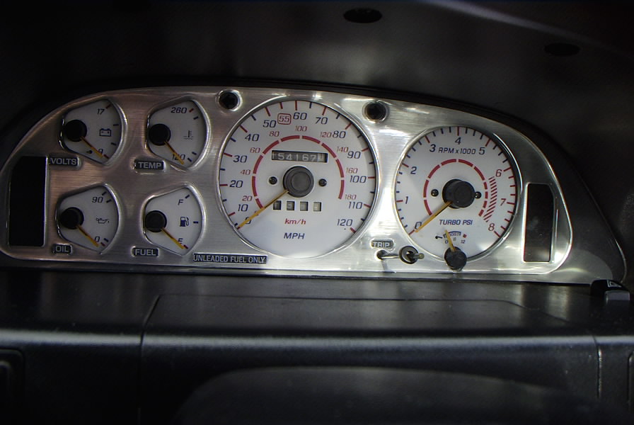 Car dashboard with voltmeter, temperature, oil, fuel, speedometer, and tachometer gauges. Odometer shows 54167 miles