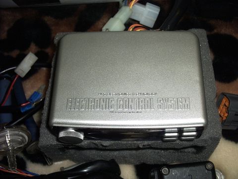 1989 Ford Probe - A silver electronic control system unit is shown with various wires and connectors attached.