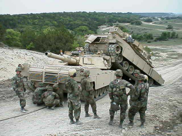 Tank with soldiers on a dirt road, trees in background