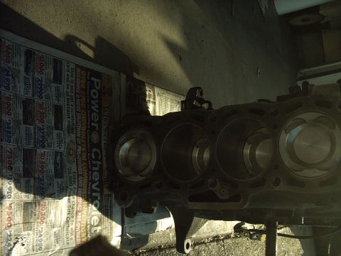 1989 Ford Probe - An engine block with visible pistons sits on a surface covered with newspaper advertisements.