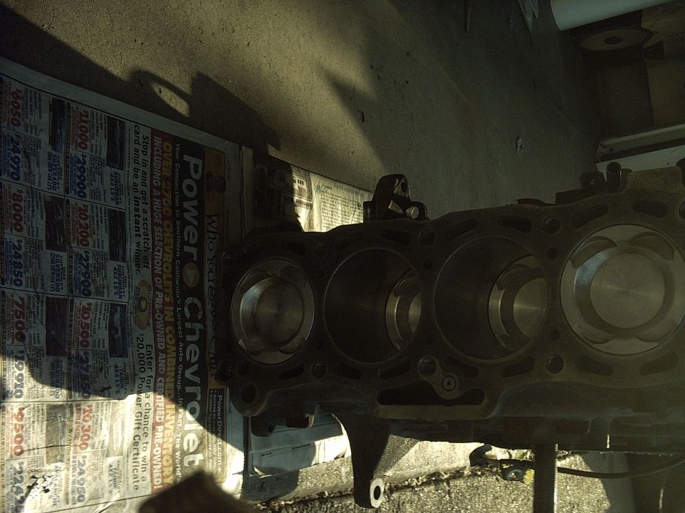 Engine block with pistons, viewed from the side, resting on newspaper