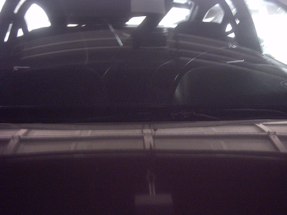Dark car interior with dashboard and windshield visible, showing wiper blades and reflections