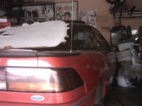 1989 Ford Probe - Rear view of a red 1989 Ford Probe, showing the taillight and Ford emblem. A white panel is resting on the roof.