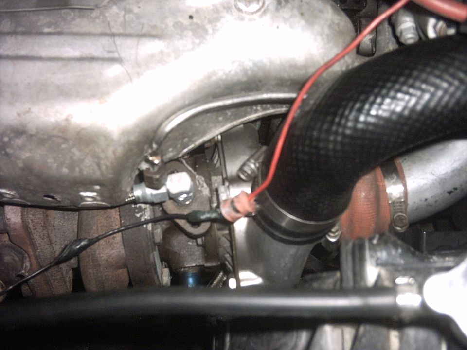Underhood close-up of a starter, wiring, and large black coolant hose against the block