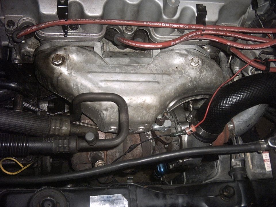 Engine bay with turbocharger and exhaust manifold. Red Magnecor KV85 Competition spark plug wires visible