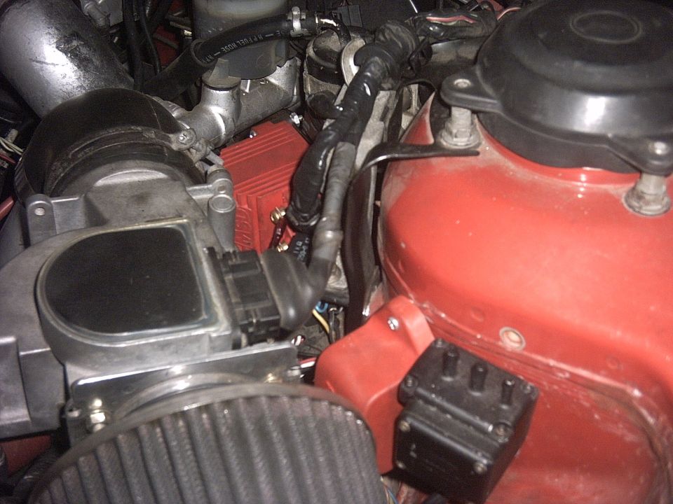 Engine bay close-up with red cam cover, cone air filter on the MAF sensor, and coil pack