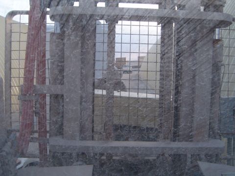 1988 Ford Bronco - A forklift is in the foreground, with a white vehicle visible in the background through a wire mesh.