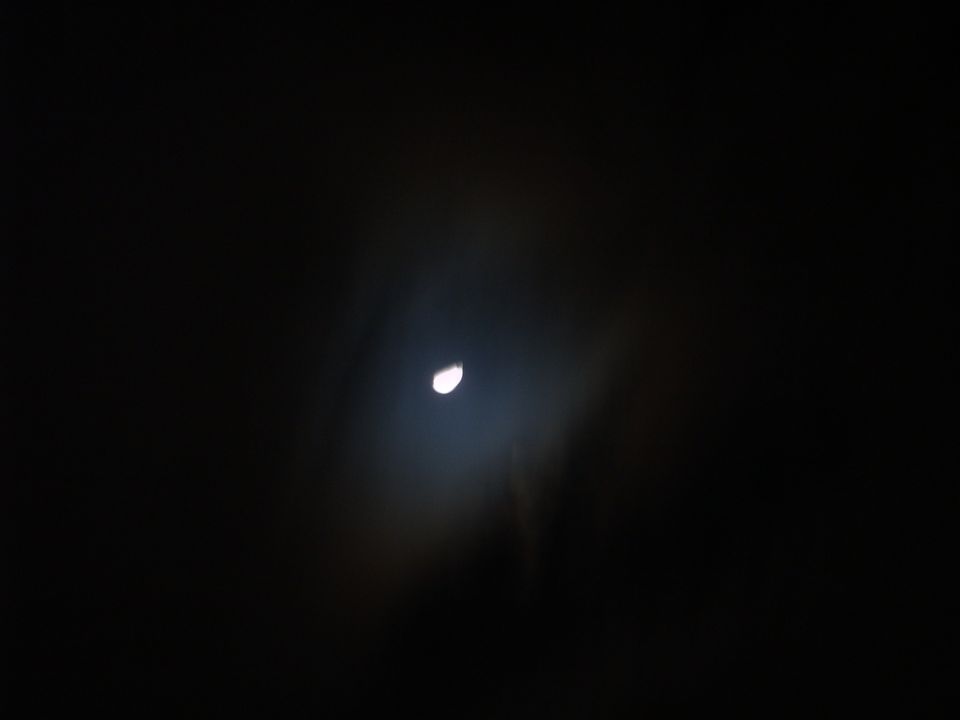 Moon partially illuminated in a dark sky with clouds, SUPERMOTORS.net logo at bottom right
