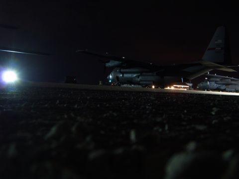 1988 Ford Bronco - A large military cargo plane sits on a tarmac at night, illuminated by ground lights.
