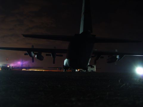 1988 Ford Bronco - Multiple military transport aircraft are visible on the tarmac at night, illuminated by ground lights and aircraft landing lights.