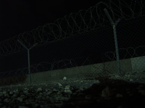 1988 Ford Bronco - Nighttime scene of a fence with barbed wire and a concrete barrier.