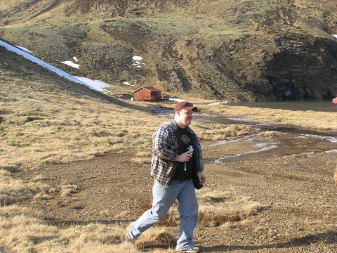 2001 Jeep Wrangler - A person walks through a dry, grassy landscape with a small red cabin visible in the distance.