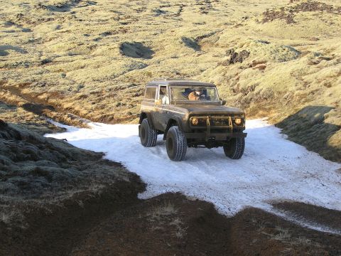 2001 Jeep Wrangler - A classic Ford Bronco navigates a snowy, off-road path in a landscape.