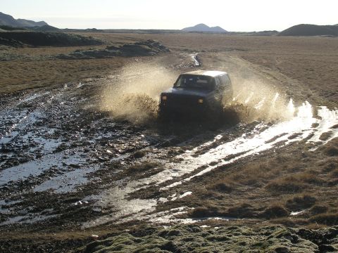 2001 Jeep Wrangler - Jeep TJ driving through mud and water, kicking up a large spray.