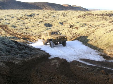 2001 Jeep Wrangler - This classic K5 Blazer navigates a challenging off-road terrain with patches of snow and mud under a clear sky.