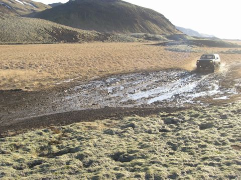 2001 Jeep Wrangler - Jeep TJ navigates a challenging muddy path with hills in the background.
