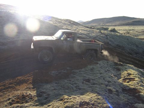 2001 Jeep Wrangler - Pickup truck navigates a challenging off-road terrain with moss and rocks.