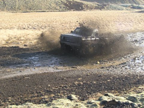 2001 Jeep Wrangler - A pickup truck powers through a muddy trail, sending dirt and water flying.