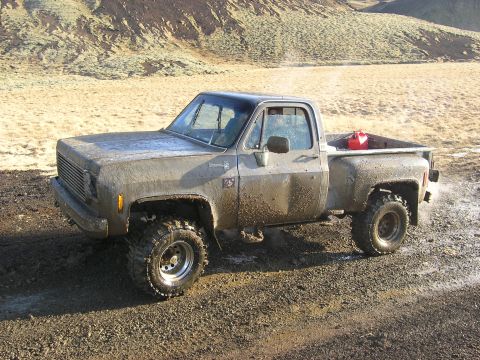 2001 Jeep Wrangler - This heavily muddied pickup truck appears to be equipped for off-road adventures, complete with large tires and a gas can in the bed.
