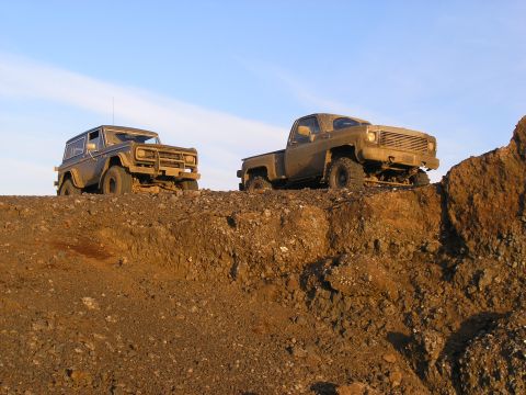 2001 Jeep Wrangler - Two off-road vehicles, a Bronco and a pickup truck, navigate a challenging dirt terrain under a bright sky.