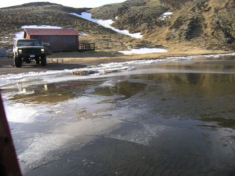 2001 Jeep Wrangler - A white Jeep Wrangler is parked near a building beside a partially frozen lake on a sunny day.