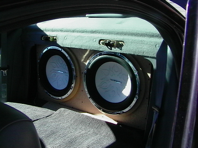 Two 12-inch subwoofers in a trunk-mounted box with chrome rings and flame-graphic cones