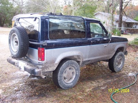 1993 Ford Bronco - Mud-covered 1989 Ford Bronco II with spare tire mounted on rear door.