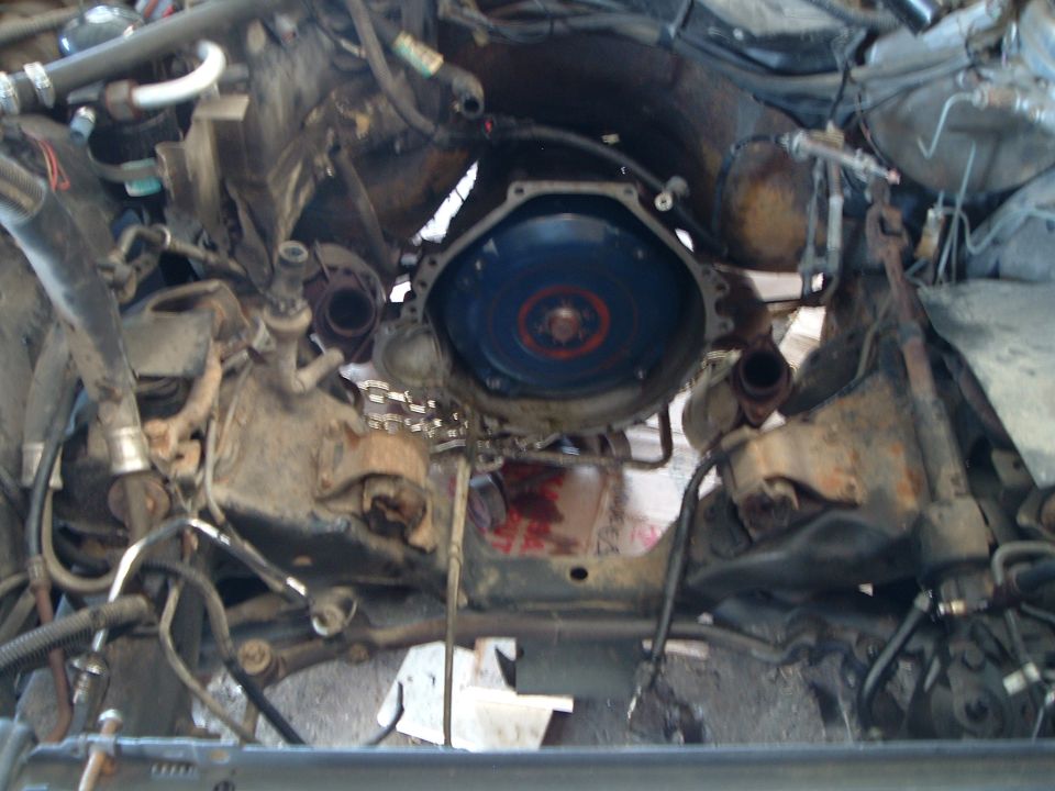 Empty engine bay with engine removed, exposing blue torque converter and transmission bellhousing