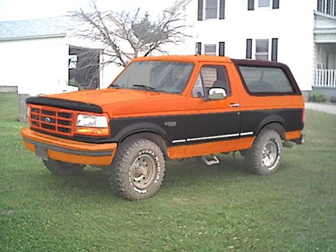 1994 Ford Bronco - This two-tone Ford Bronco is shown from a three-quarter front angle, parked on a grassy lawn.