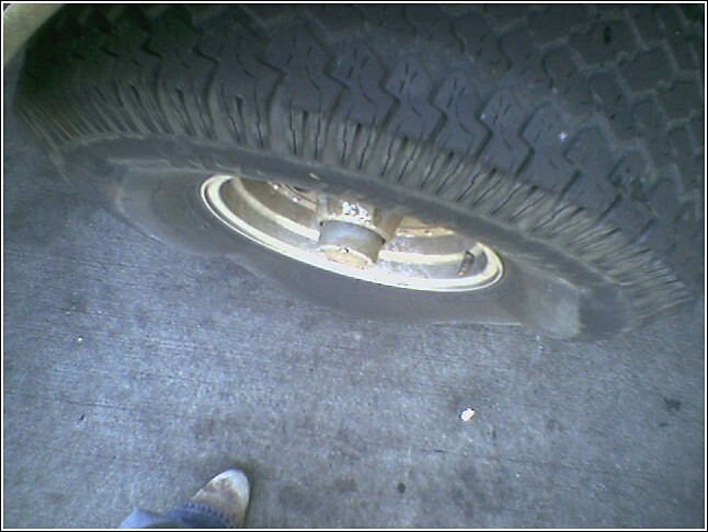 Close-up of a worn tire and wheel on a concrete surface