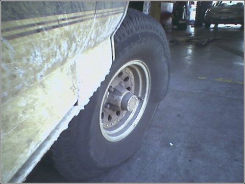 1993 Ford Bronco - A close-up view of a vehicle's tire and fender shows dirt and wear, with another vehicle visible in the background.