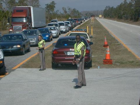 2000 Ford Crown Victoria - Police officers manage traffic flow during a highway backup, with numerous vehicles lined up.