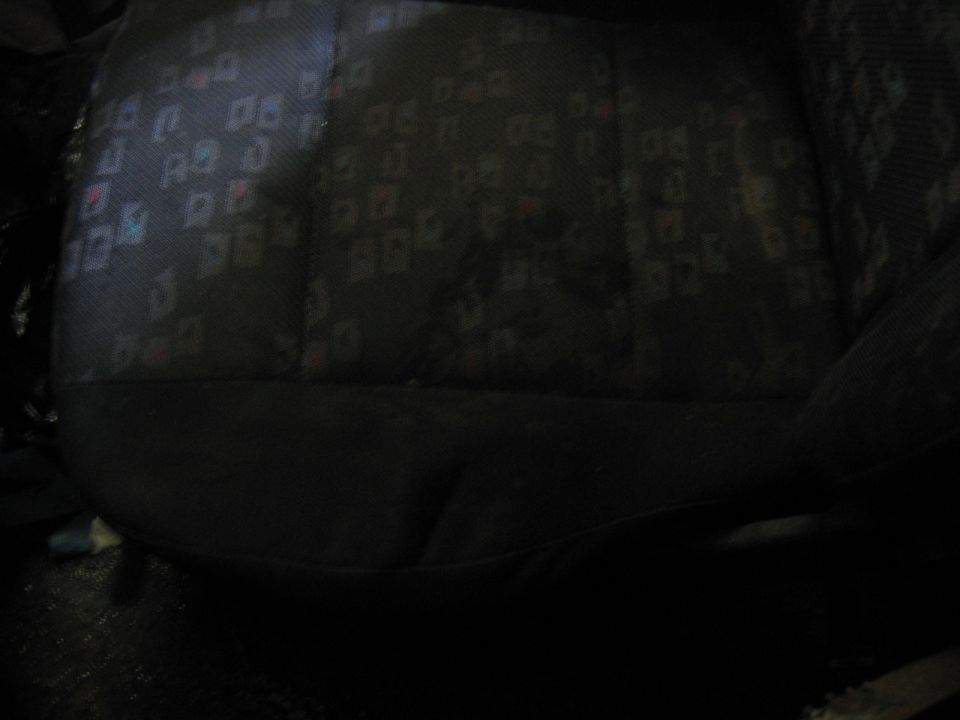 Dark car seat fabric with a repeating geometric pattern of squares and rectangles in blue, red, and white