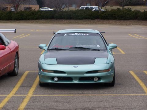1993 Ford Probe - A light blue 1993 Ford Probe is parked in a lot, showing its front end and a black hood.