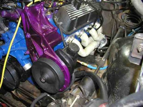 1988 Ford Bronco - Close-up view of an engine bay a custom painted purple power steering pump bracket and various engine parts.