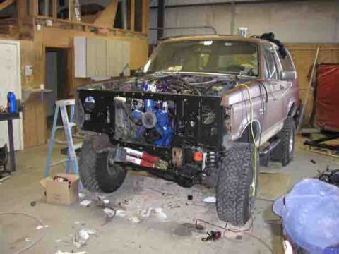 1988 Ford Bronco - A 1988 Ford Bronco is undergoing repairs in a garage, with its engine compartment open.