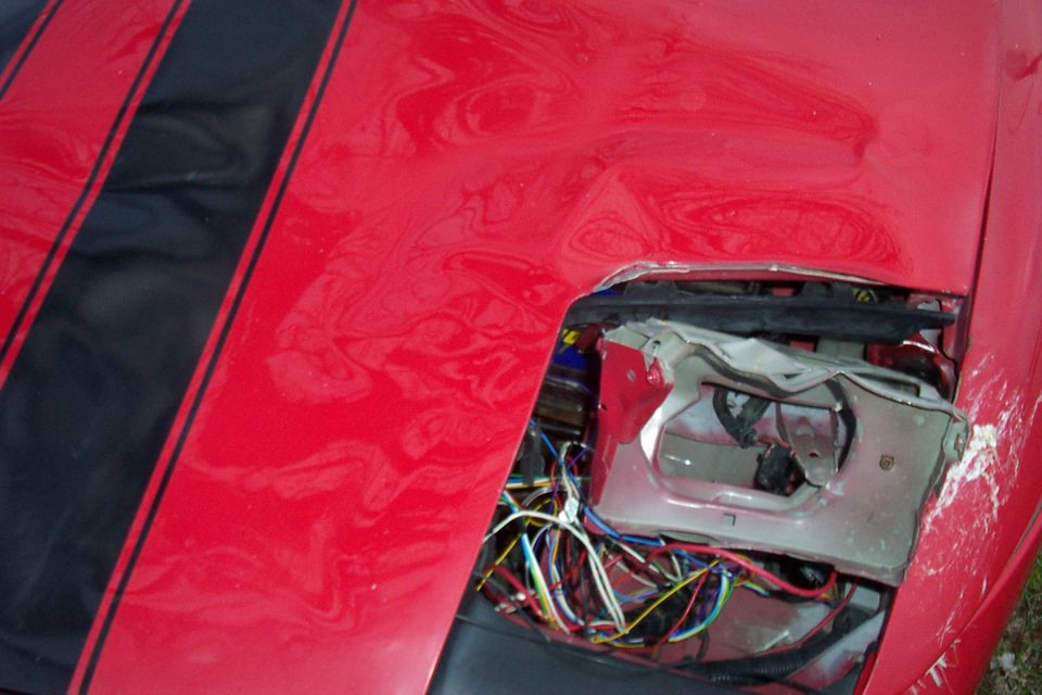 Red hood with black stripes, missing pop-up headlight exposing bracket and colorful wiring