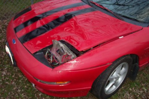 1993 Ford Probe - Front view of a red 1993 Ford Probe showing damage to the headlight area and hood.