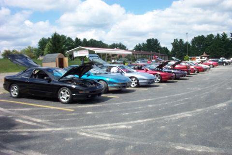 1993 Ford Probe - A row of Ford Probes are parked in a lot, most with hoods or trunks open, under a partly cloudy sky.
