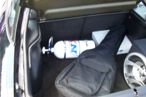 1993 Ford Probe - The trunk of a car contains a nitrous oxide tank, a guitar in a case, and other items.