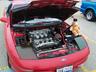 1993 Ford Probe - A red car's engine compartment is open, revealing its V6 engine and a stuffed bear.