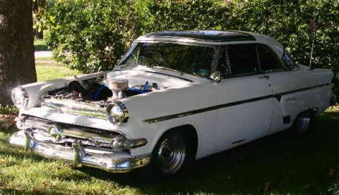 1954 Ford Crestline - A white 1954 Ford Crestline coupe is parked outdoors with its hood open, revealing the engine.