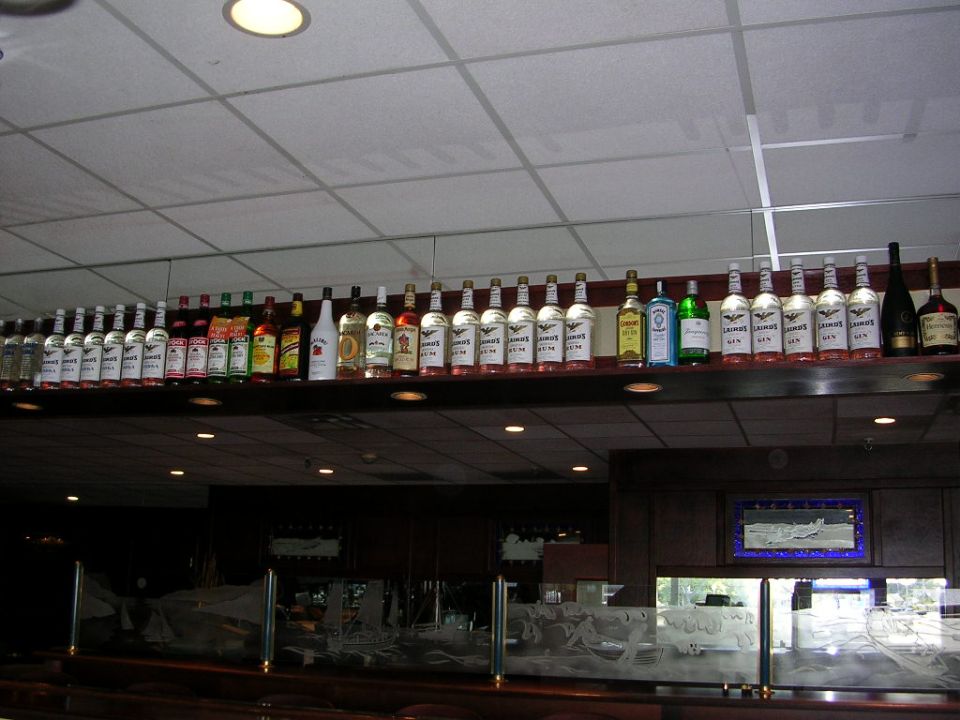 Row of liquor bottles on a shelf above an etched-glass bar