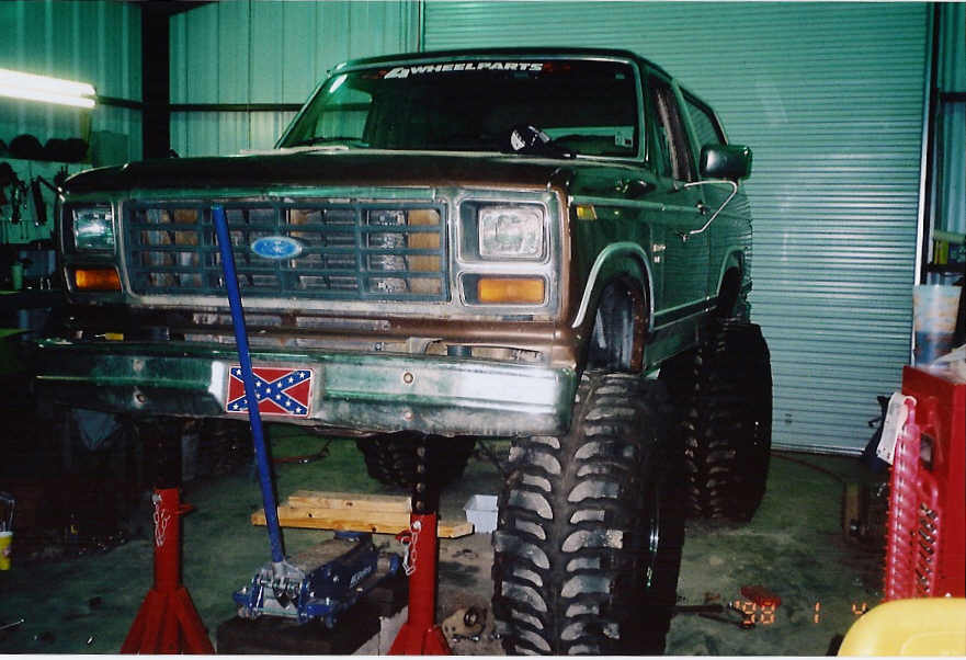 Green Ford Bronco on jack stands, lifted with large tires, front view