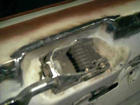 1990 Ford Bronco - Extreme close-up of a white body panel where a rusted, cut-out section has been patched with welded sheet metal, showing grinder marks and…