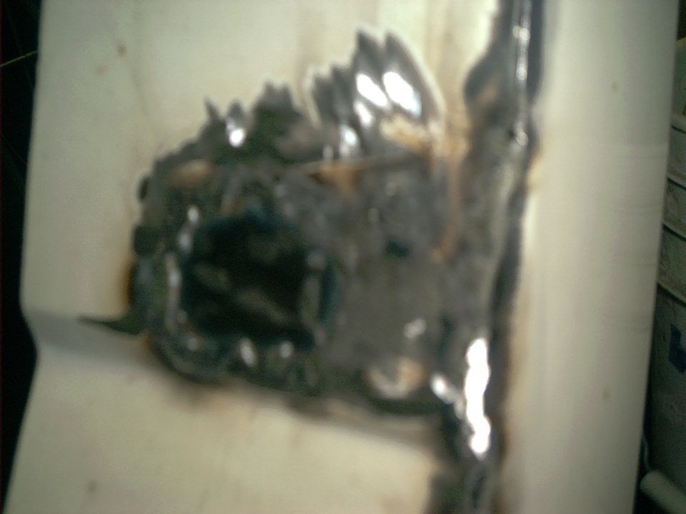 Blurry close-up of ground and welded rust repair on a white body panel