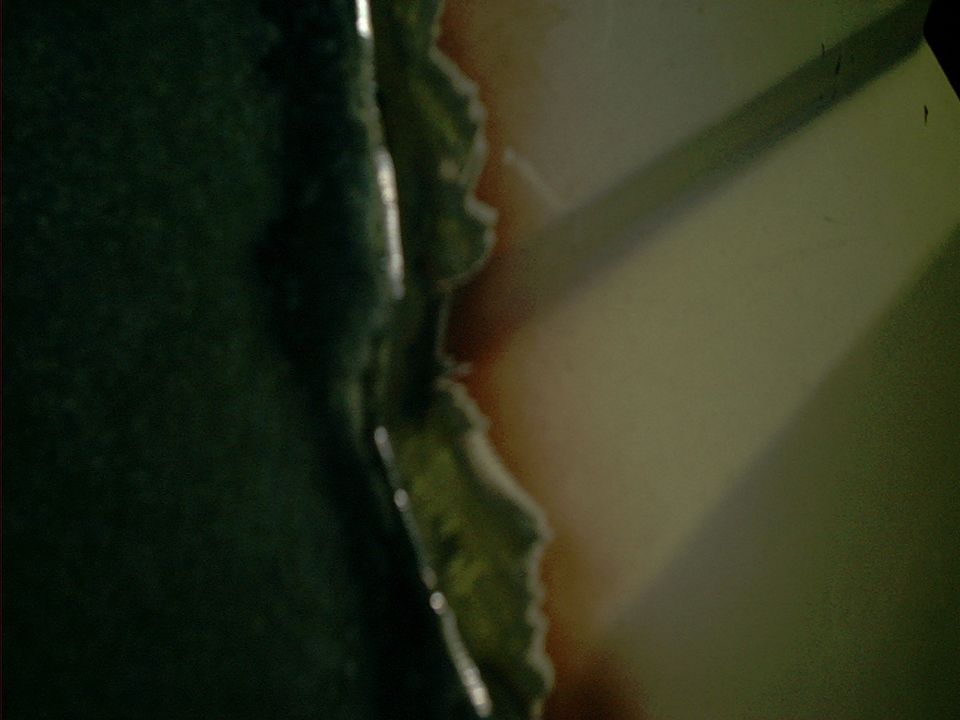 Torn metal edge with green paint and rust, close-up