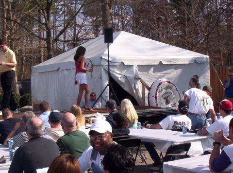 1986 Ford Bronco - An outdoor event with a tent, stage, and audience. A woman is presenting on the stage.