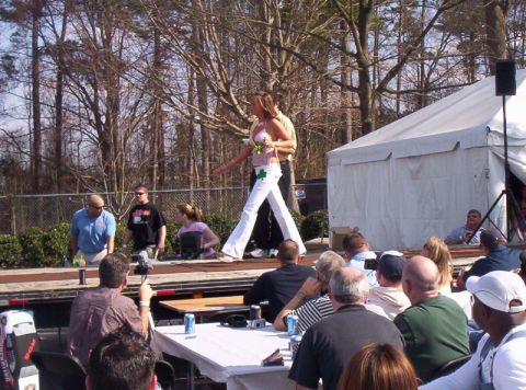 1986 Ford Bronco - An outdoor event is underway with a stage set up for a contest and an audience seated at tables.