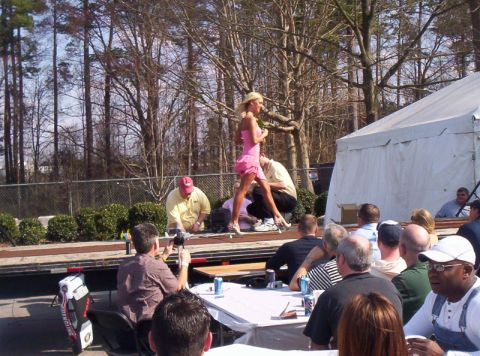 1986 Ford Bronco - A Hooters Bikini Contest is underway with a contestant on stage and an audience seated at tables.